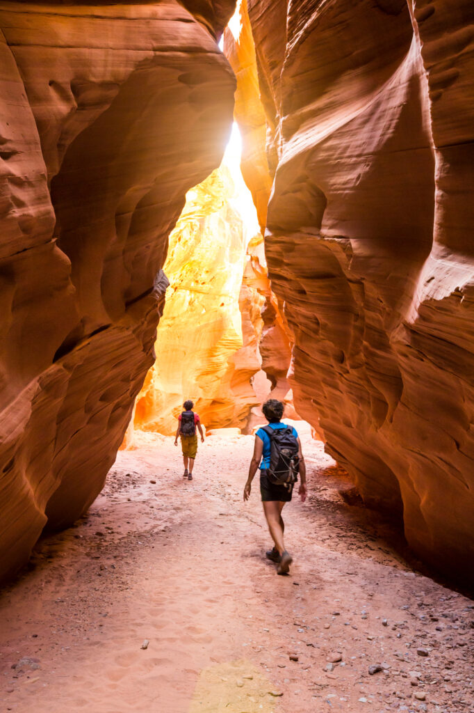 Two people walking through a cave in the desert.