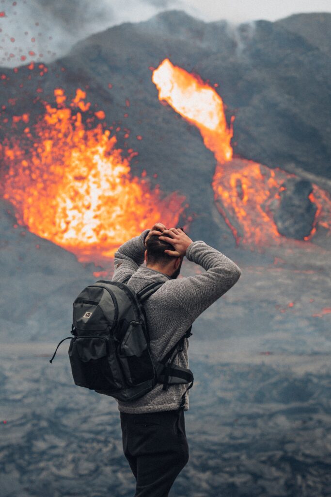 A person with a backpack standing in front of a fire.